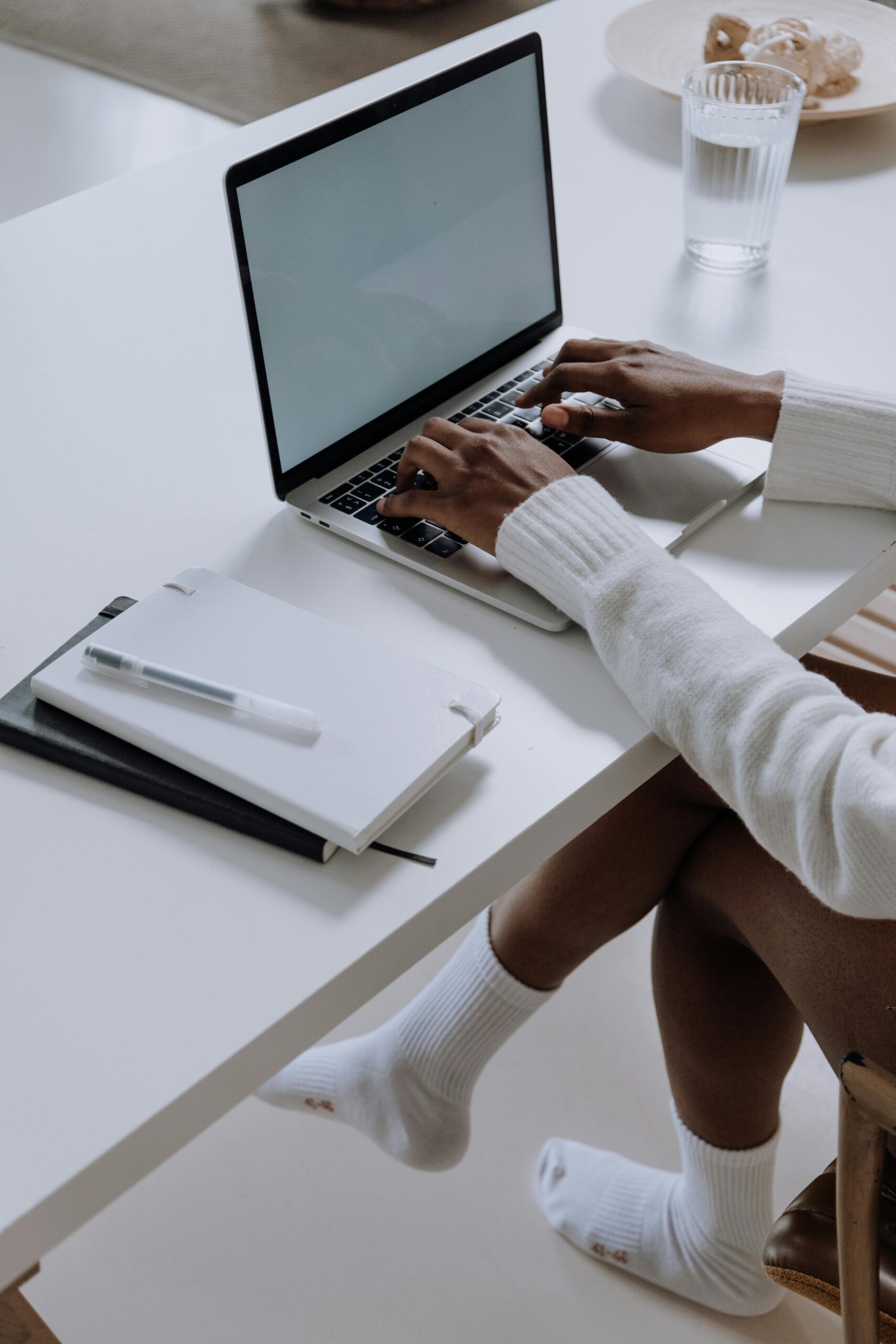Person sitting at a table, hands typing on a laptop.