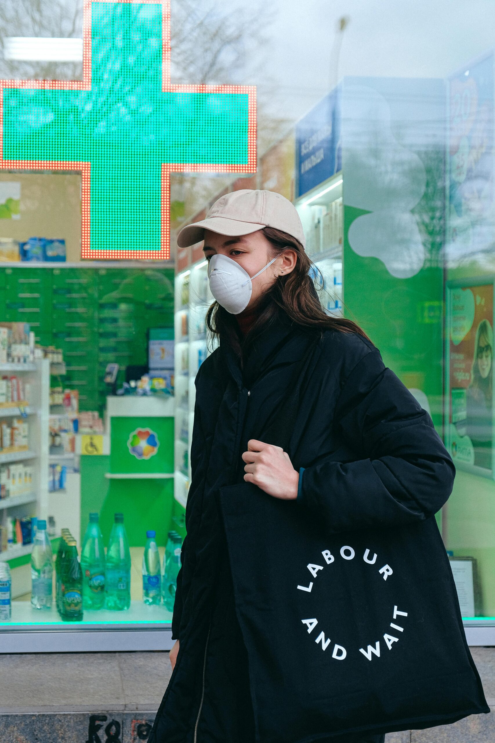 Woman wearing a face mask in front of a pharmacy.